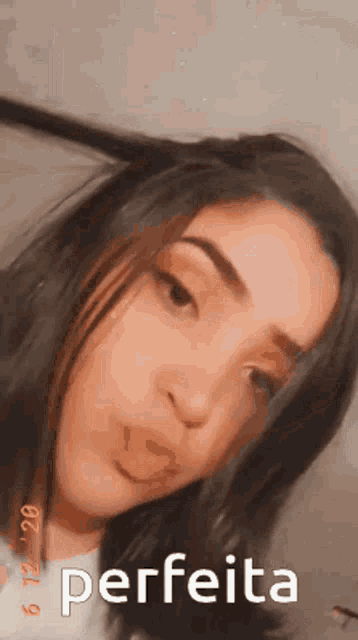 a girl is taking a selfie with the word perfeita written on the bottom of her face .