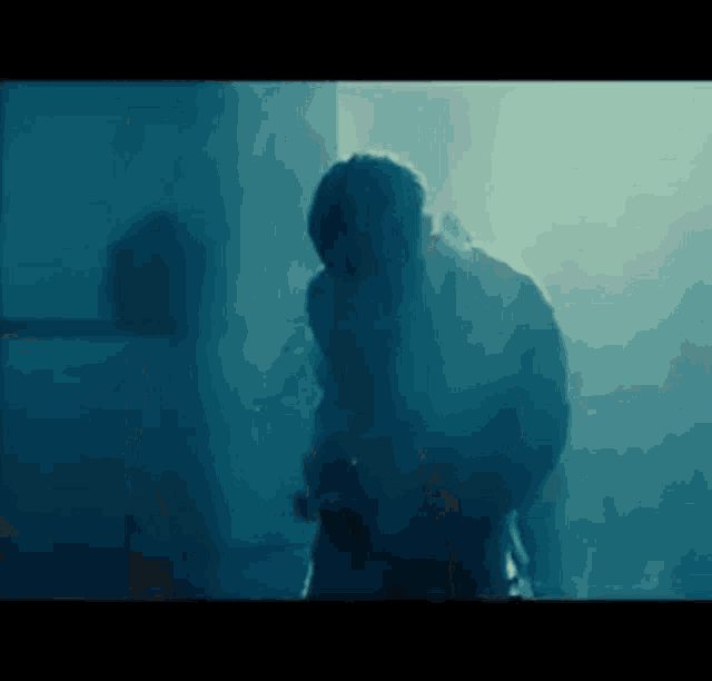 a man is standing in a dark room with smoke coming out of the ceiling .