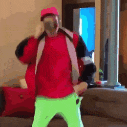 a man wearing a red jacket and neon green pants is dancing in a living room