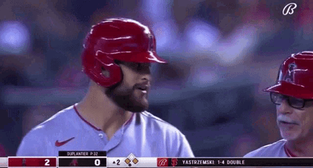 a baseball player wearing a red helmet is talking to another player .