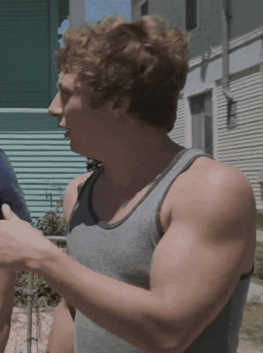 a man in a grey tank top is pointing