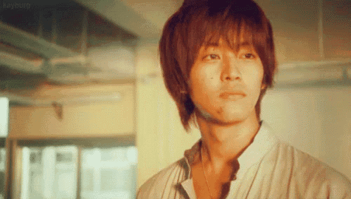 a close up of a young man 's face with a necklace around his neck .