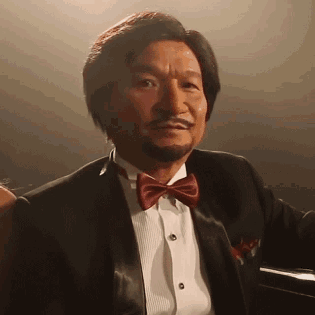 a man wearing a tuxedo and bow tie looks at the camera