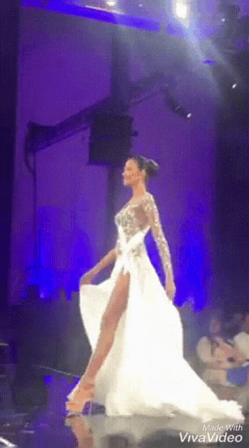 a woman in a long white dress is walking down a runway made with viva video
