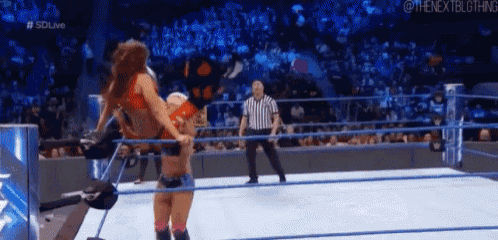 two women are wrestling in a ring with a referee in the background .