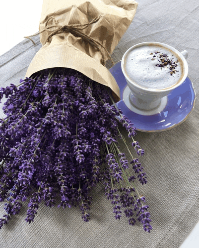 a cup of coffee next to a bunch of lavender