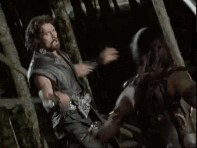 a man and a woman are fighting in a forest .
