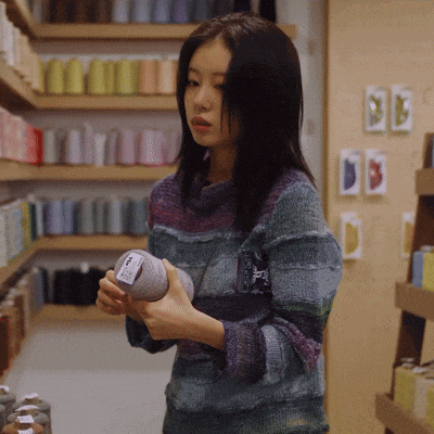 a woman in a striped sweater holds a ball of yarn with a label on it that says ' wool '