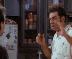 a man is talking to another man in a kitchen with a refrigerator that says item on it .