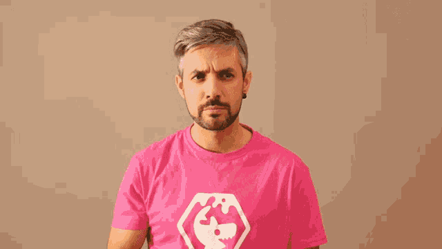 a man wearing a pink t-shirt with a bird on it is thinking