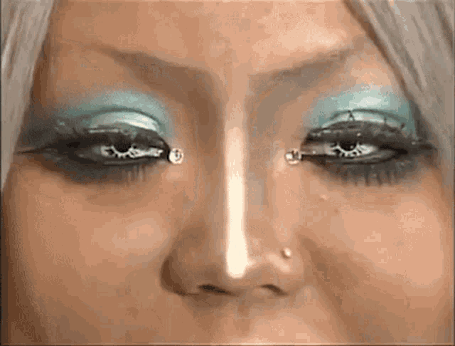 a close up of a woman 's eyes with blue eye shadow and rhinestones on them .