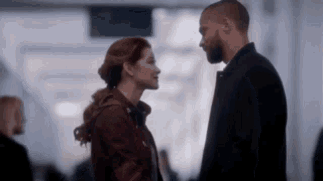 a man and a woman are standing next to each other and looking at each other in a hallway .
