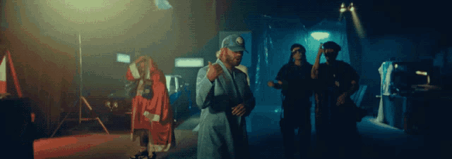 a man wearing a hat with the letter r on it stands in a dark room