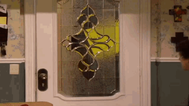 a stained glass door with a cross on the wall