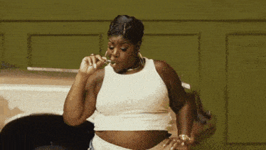 a woman in a white tank top is blowing bubbles
