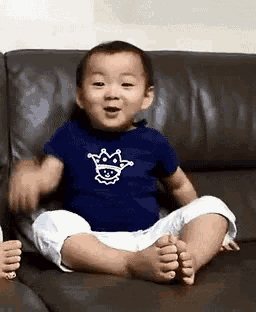 a baby is sitting on a couch and smiling .