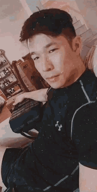 a young man wearing a black under armour shirt is taking a selfie
