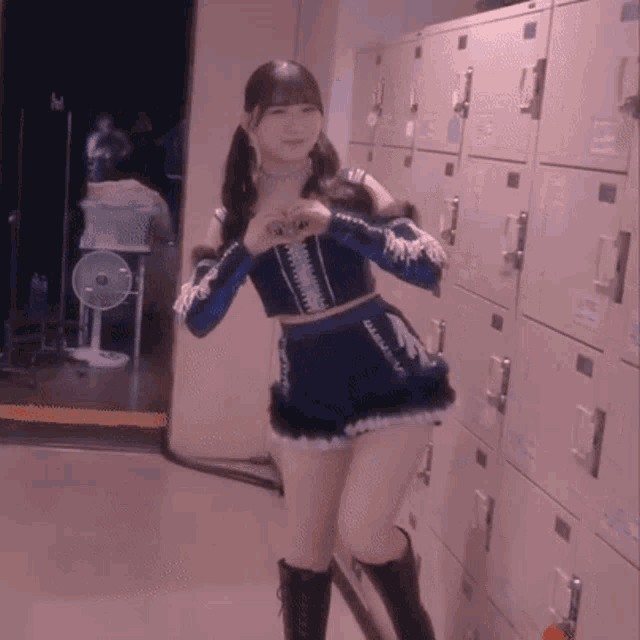 a woman in a blue dress stands in front of lockers
