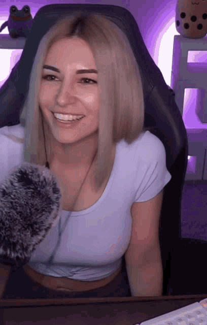 a woman in a white shirt is smiling while sitting in a gaming chair