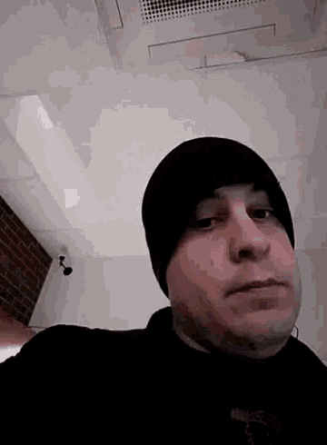a man wearing a black beanie is looking at the camera .