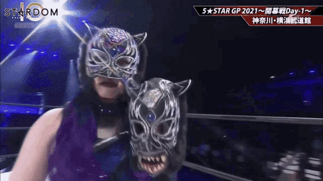 a woman in a tiger mask is standing in a ring with a stardom logo on the bottom