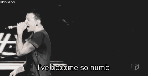 a man is singing into a microphone with the words `` i 've become so numb '' below him .