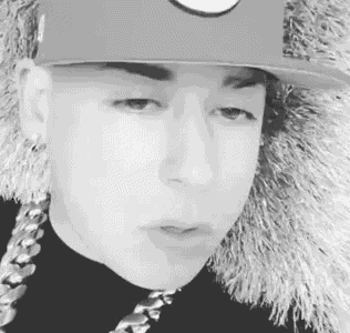 a black and white photo of a man wearing a hat and chains