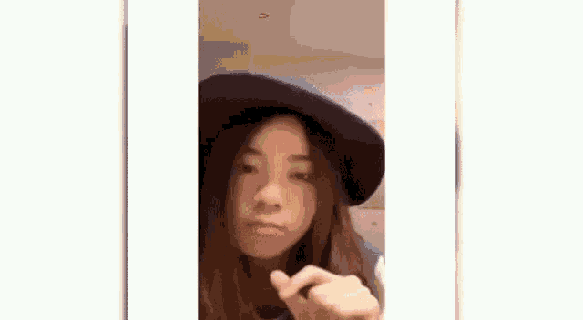 a young woman wearing a blue hat is making a peace sign .