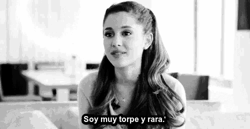 ariana grande is sitting on a couch in a black and white photo and saying `` soy muy torpe y rara '' .