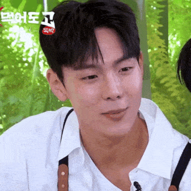 a young man wearing a white shirt and suspenders is making a funny face .