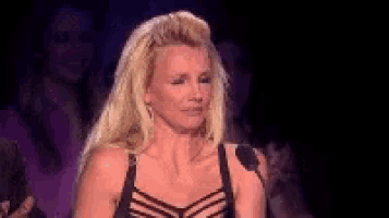 a blonde woman in a black bra is standing in front of a microphone .