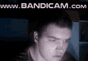 a man wearing ear buds is looking at a computer screen with the words www.bandicam.com above him .
