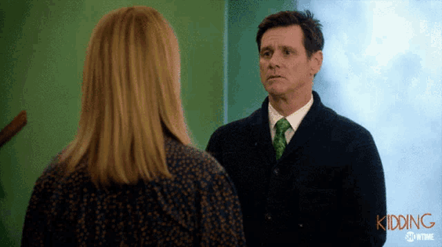 a man in a suit and tie stands next to a woman in a showtime ad for kidding