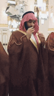 a man with a beard is wearing a brown robe and a red and white checkered head scarf