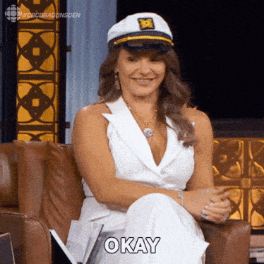 a woman wearing a captain 's hat is smiling and says okay