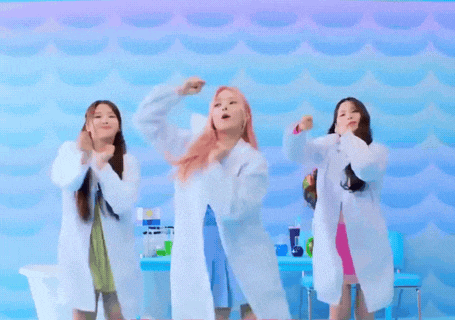 three women in lab coats are dancing in front of a blue background