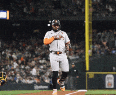 a baseball player wearing a giants uniform is running towards the base