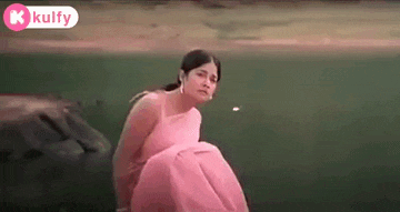 a woman in a pink dress is sitting on the edge of a lake .