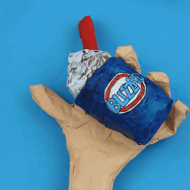 a hand is holding a blizzard ice cream cone