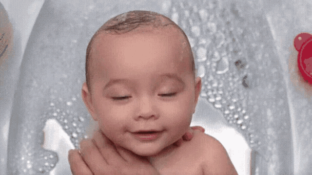 a baby smiles while taking a bath in a bathtub