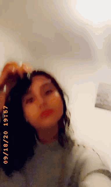 a woman is taking a selfie in a room with a white wall behind her .
