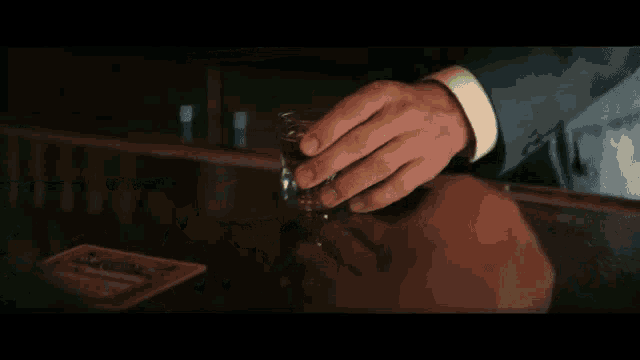 a man in a suit holds a glass of whiskey