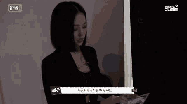 a woman standing in front of a window with the word cube written on it