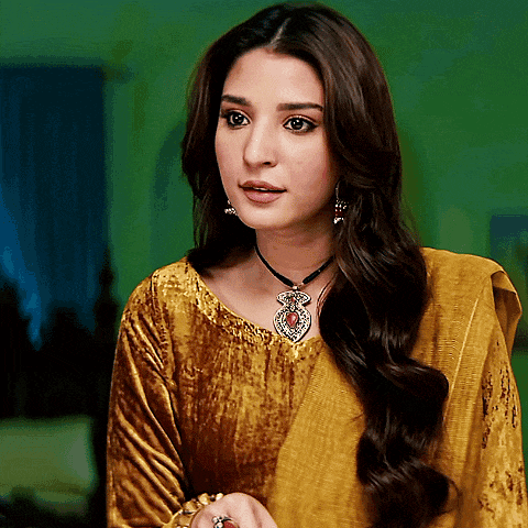 a woman wearing a yellow dress and a necklace with a red stone