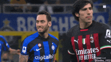 a soccer player wearing a digitalbits jersey stands next to another player wearing an emirates fly better jersey