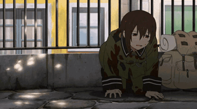 a girl in a green coat is crawling on the ground next to a backpack