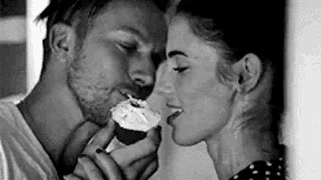 a man is feeding a cupcake to a woman who is kissing him .