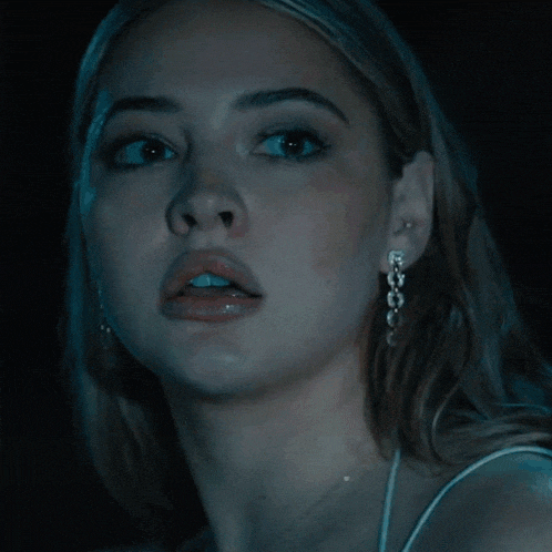 a close up of a woman 's face with a necklace and earrings
