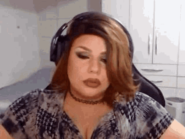 a woman wearing headphones and a choker is making a funny face .