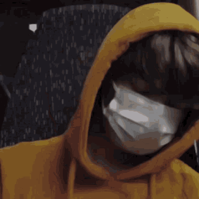 a person wearing a mask and a yellow hoodie